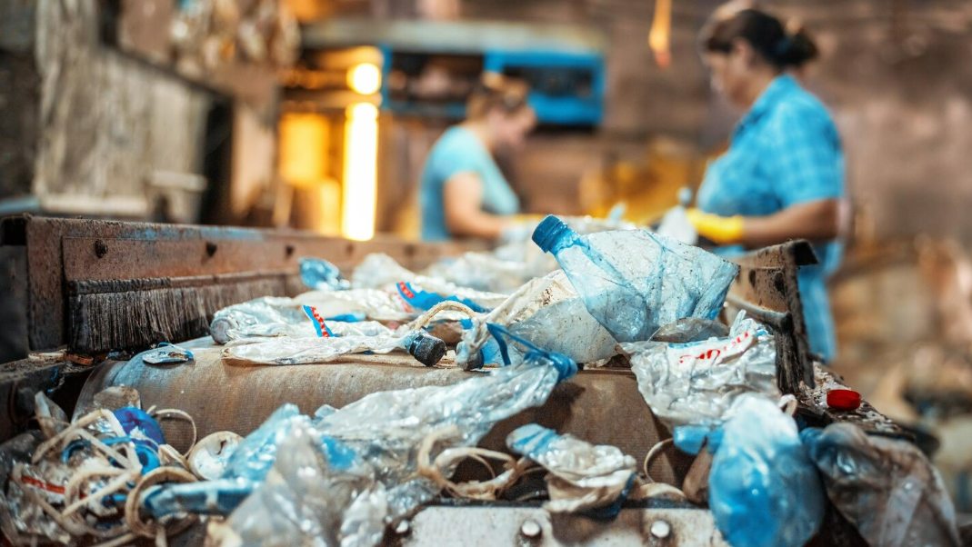 Esteira de triagem em uma central de reciclagem com garrafas plásticas, ilustrando a etapa de segregação e destinação correta dentro de um Plano de Gerenciamento de Resíduos Sólidos (PGRS).